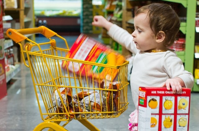 ショッピングカートに商品を入れる子供の画像。
